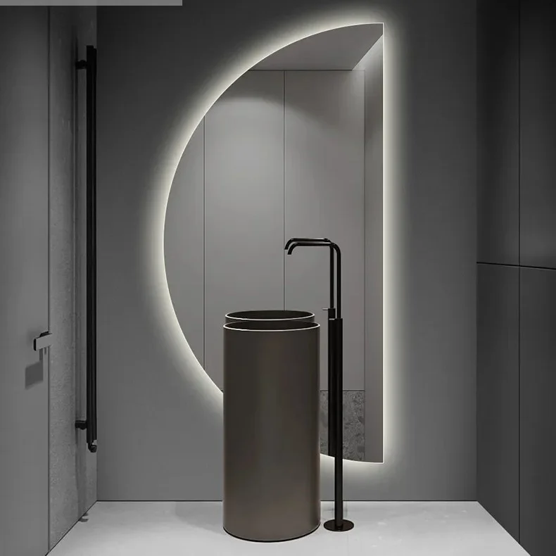 Elegance Luxury Half Moon Glow mirror with cool white backlighting, mounted behind a modern black cylindrical pedestal sink.