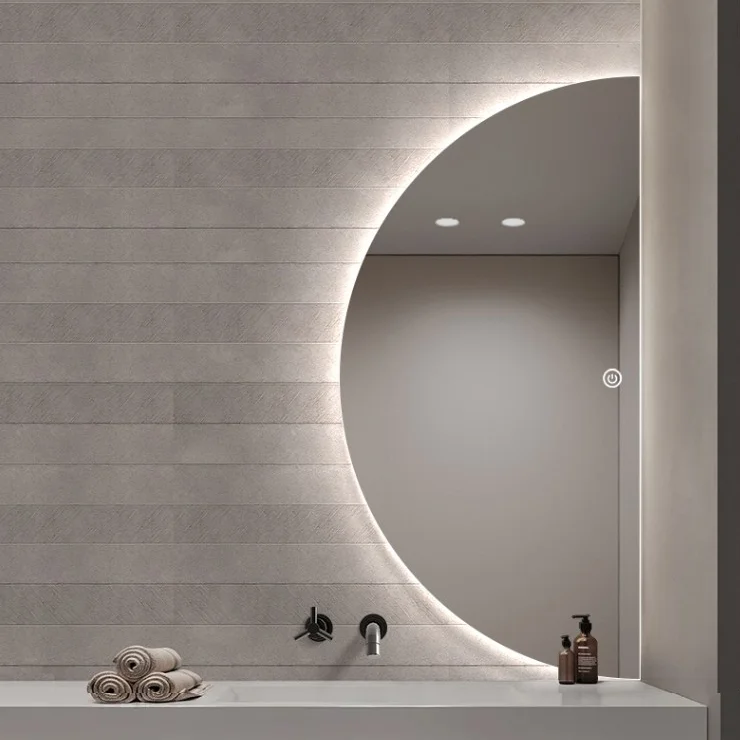 Elegance Luxury Half Moon Glow mirror with warm backlighting, mounted on a textured grey wall above a white countertop sink.