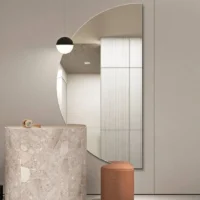 Elegance Luxury Half Moon Glow mirror with warm backlighting, mounted on a dark grey wall above a black countertop and gold tap.