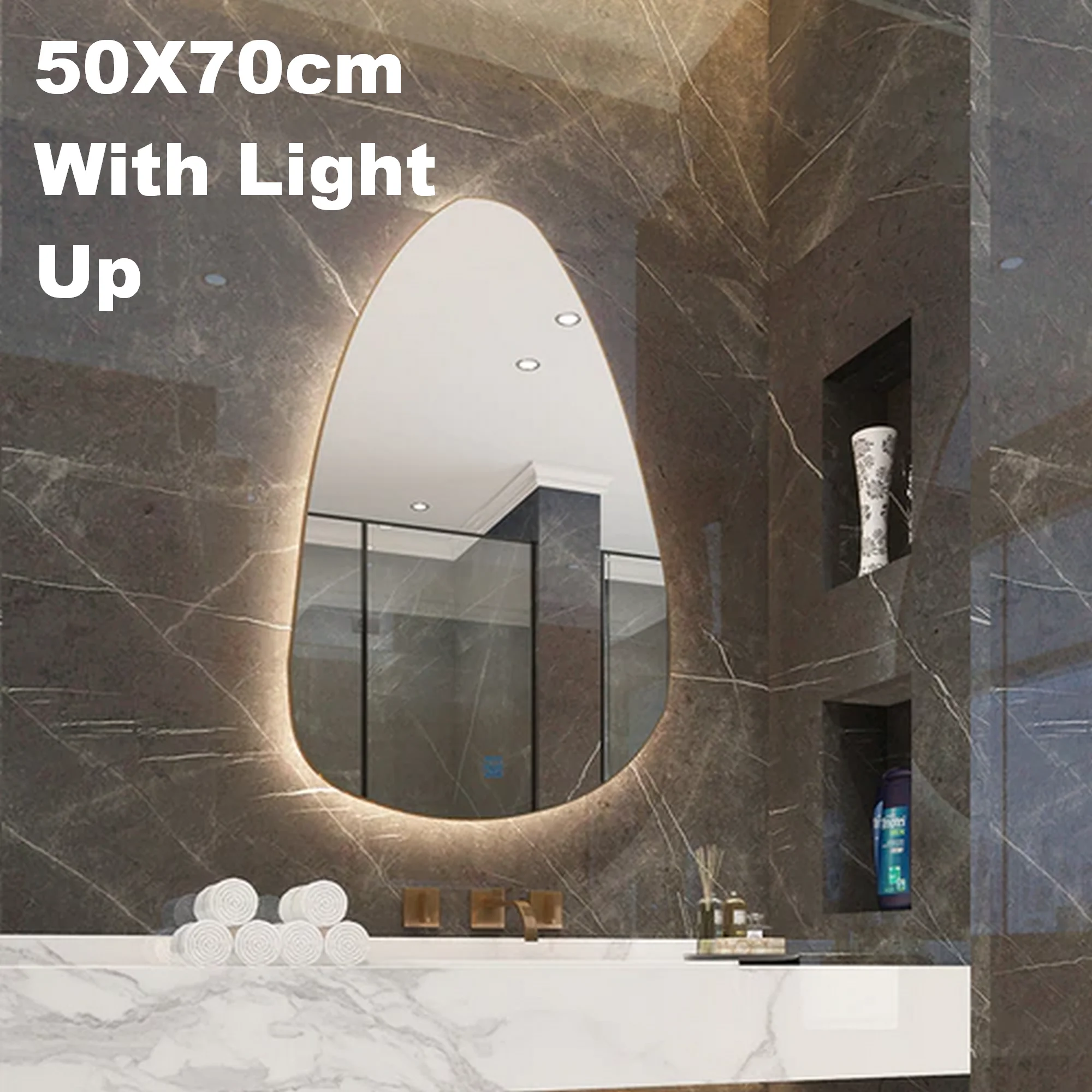 An ORGANIC OVAL VANITY MIRROR with a warm backlit glow, mounted on a dark marble bathroom wall above a white marble vanity.