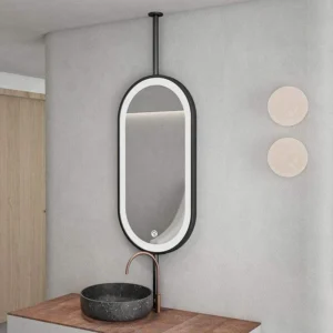 Oval backlit mirror above a wooden vanity with a dark stone sink and copper faucet in a minimalist bathroom.