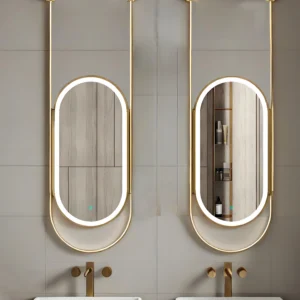Double oval backlit mirrors with gold frames mounted on a light gray tiled bathroom wall, reflecting built-in shelves and toiletries above two gold faucets and sinks.