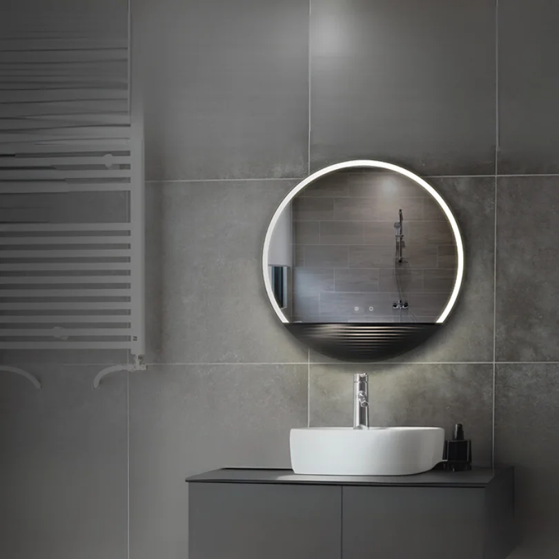 LED Half Moon Round Black Frame Mirror with cool white lighting, mounted on a grey tiled wall above a white sink and black vanity.