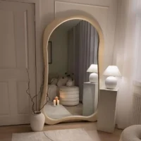 An Organic Farmhouse Bedroom Full Length Floor Mirror with a thick cream frame, leaning in a cozy, minimalist bedroom.