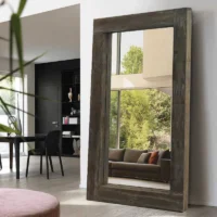 A Modern Farmhouse Rectangle Full Length Floor Wall Mirror with a thick rustic wood frame, leaning against a white wall.