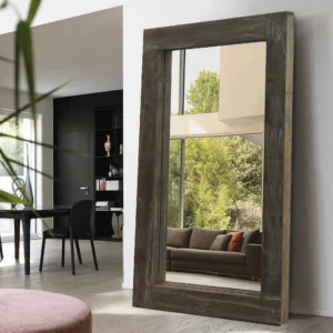 A Modern Farmhouse Rectangle Full Length Floor Wall Mirror with a thick rustic wood frame, leaning against a white wall.