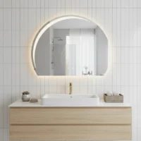 Luxury Half LED Moon Circle Mirror, a glowing crescent backlit mirror on a white tiled wall above a wood vanity with a gold faucet.