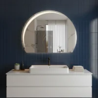 Luxury Half LED Moon Circle Mirror, a crescent-shaped backlit mirror on a navy blue tiled wall above a white vanity sink.