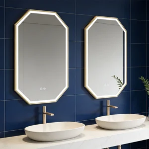 Double vanity with two white oval sinks on a marble countertop, gold-framed octagonal backlit mirrors against a dark blue tiled wall.