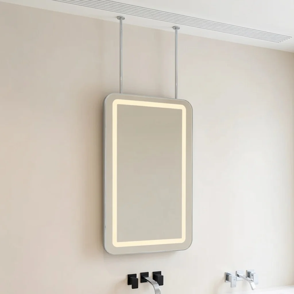 Backlit rectangular mirror mounted on a beige bathroom wall, suspended by two vertical supports.
