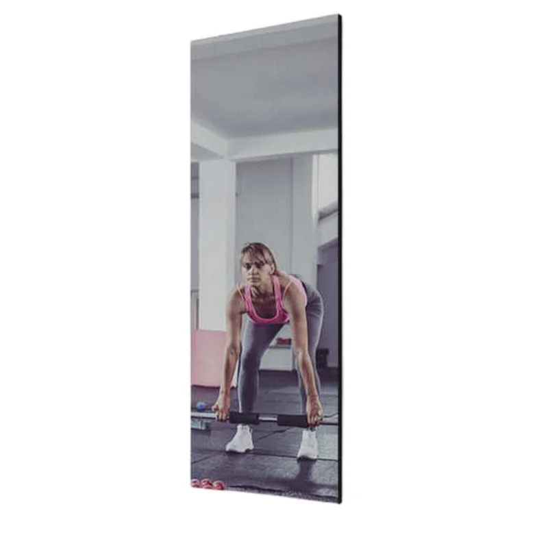 Woman in a pink top lifting a barbell in a gym, seen in a tall wall mirror's reflection