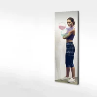 Athletic woman in profile beside a tall wall-mounted touchscreen showing translucent data overlays and graphs.