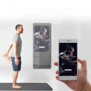 Man stretches on a mat while a smartphone and tablet display a fitness app promoting live and on-demand classes.