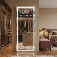 Backlit full-length mirror in a walk-in wardrobe reflecting clothes, a dresser, and shelves in a luxurious bedroom area.