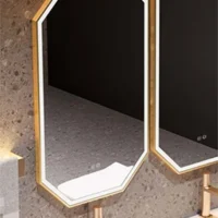 Gold-framed hexagonal mirrors with backlighting mounted above a marble vanity in a modern bathroom.